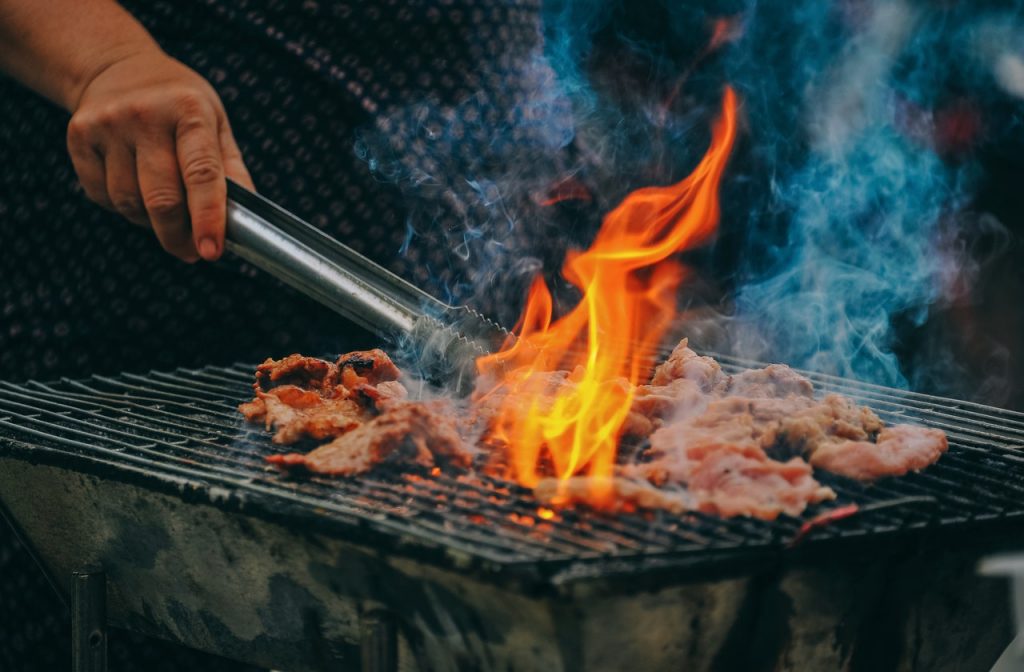 person grilling meat over an open flame